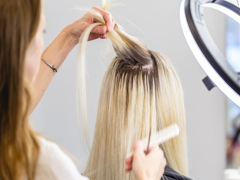 Blonde hair extensions procedure in beauty salon